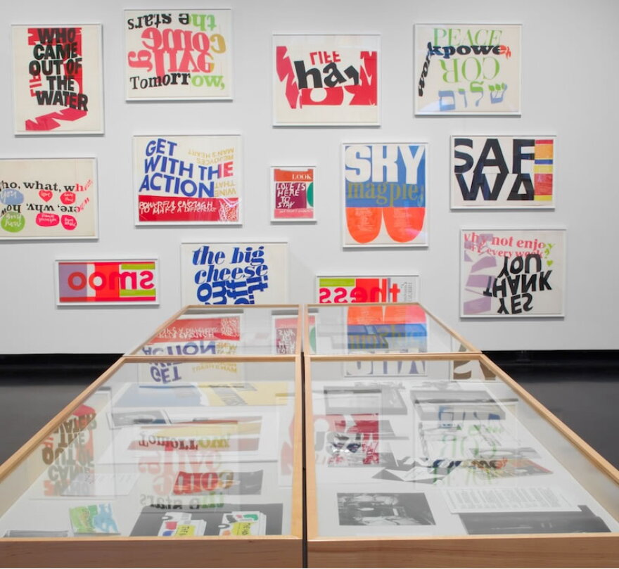 Exhibition wall of small Corita Kent prints in bright colors, mostly words