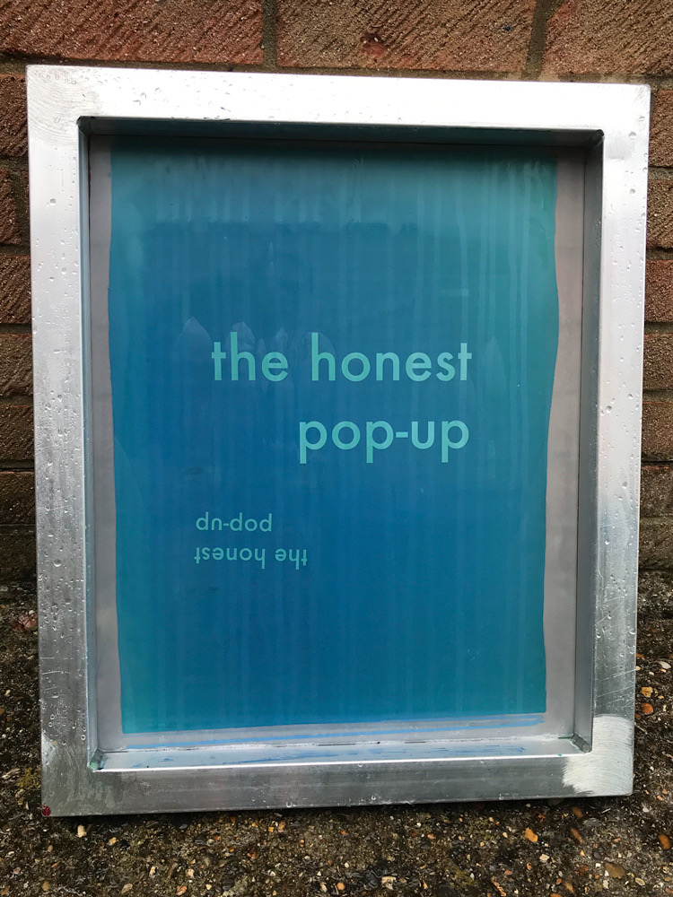 A screen with an exposed stencil held up to the light