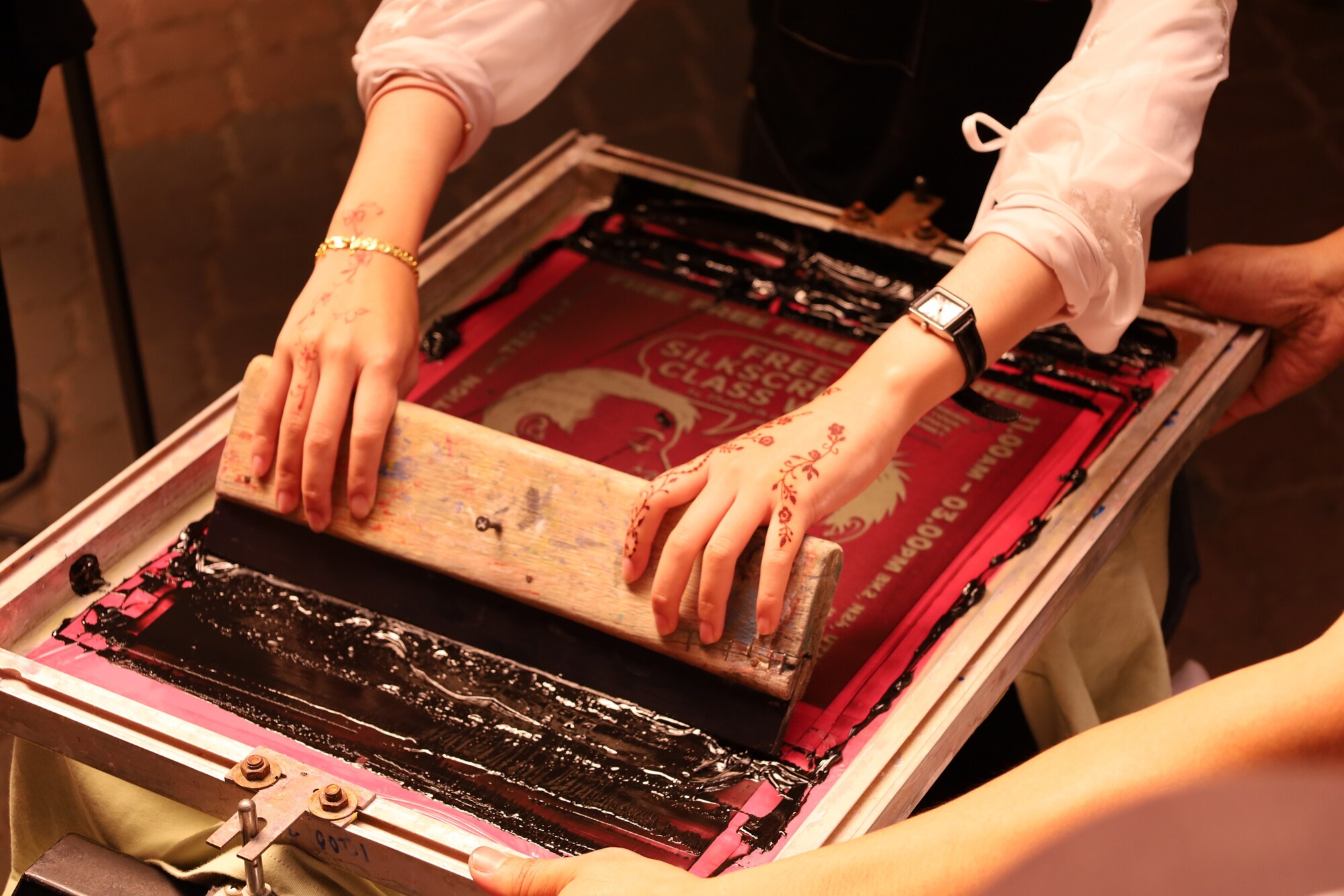 A printer pulling a squeegee across a screen