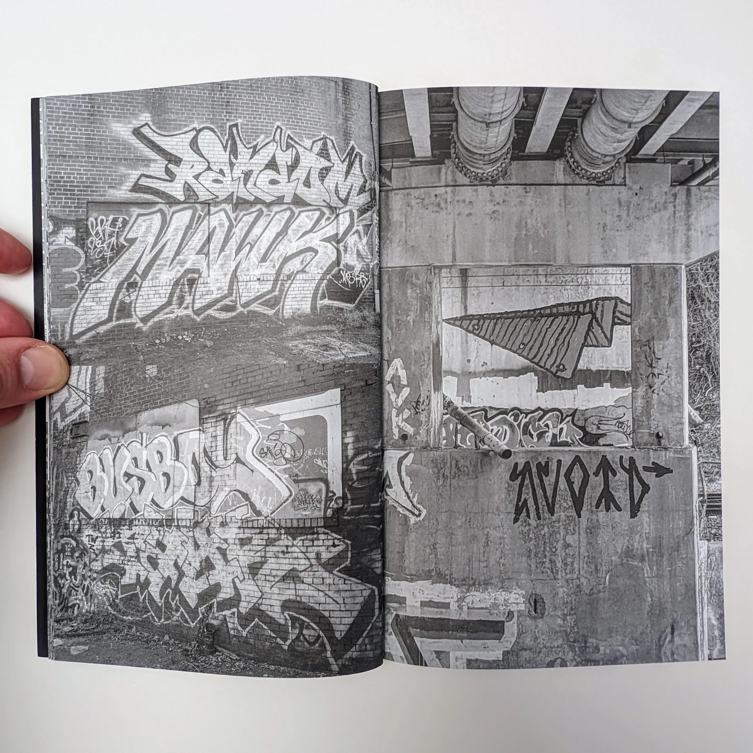 Zine spread: black and white photos of graffiti under a bridge